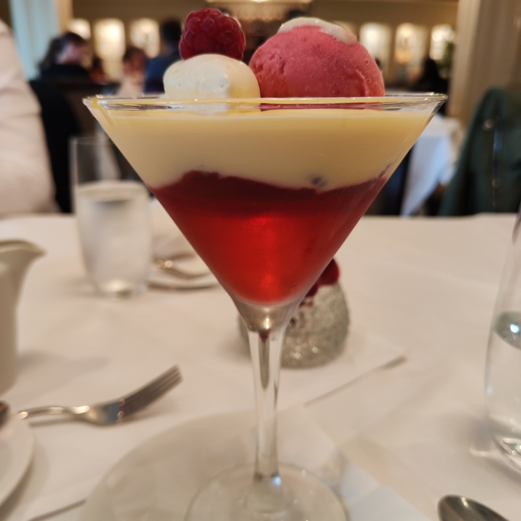 a trifle in a martini glass, topped with white and pink sorbets
